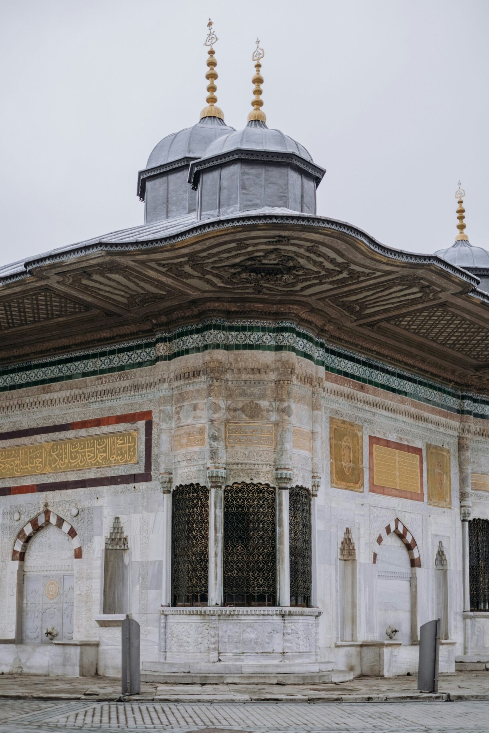 a white building with a black roof and two gold domes