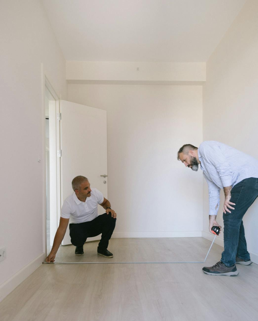 men measuring floor of a room